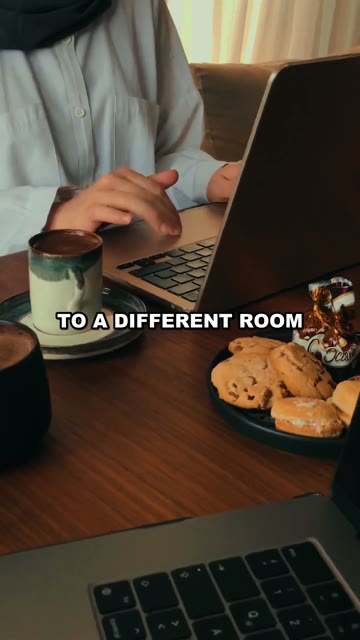 Someone working on a laptop in a cafe with coffee and cookies